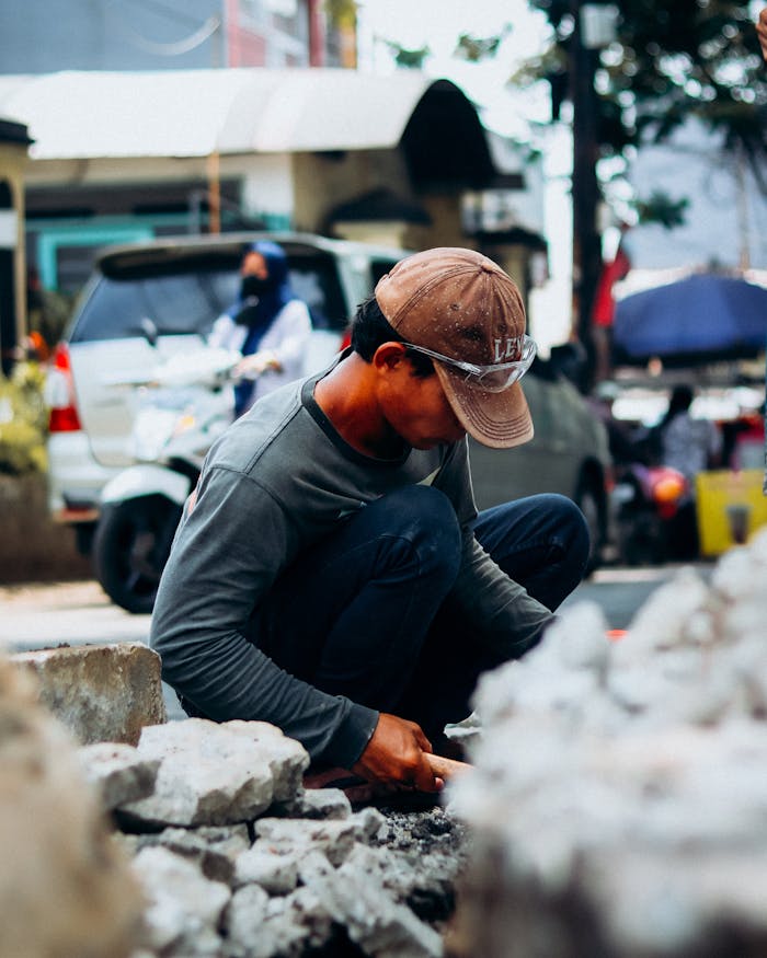 services-03 A dedicated worker repairs a sidewalk in a bustling Asian city, showcasing daily street life.