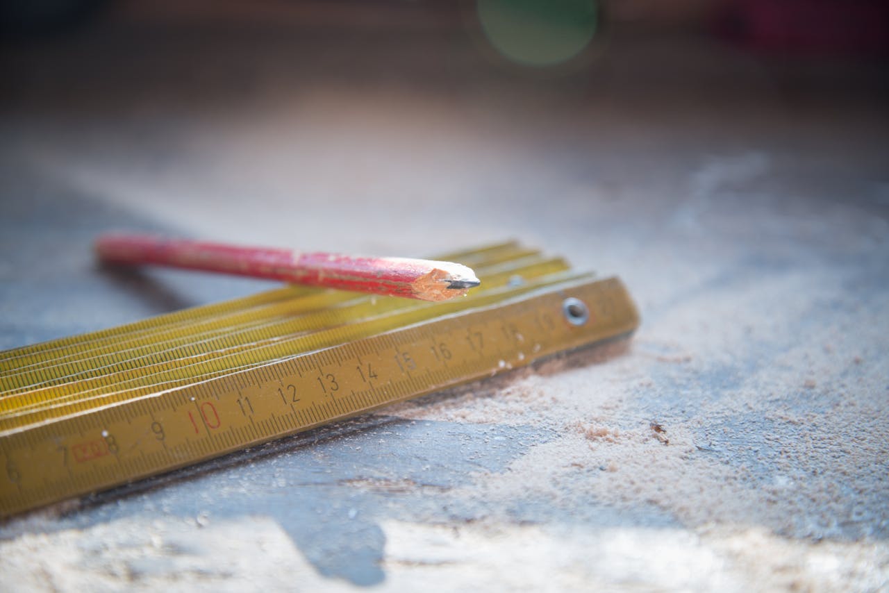 gallery-2 A red pencil and folding ruler on a dusty workshop table, symbolizing craftsmanship.